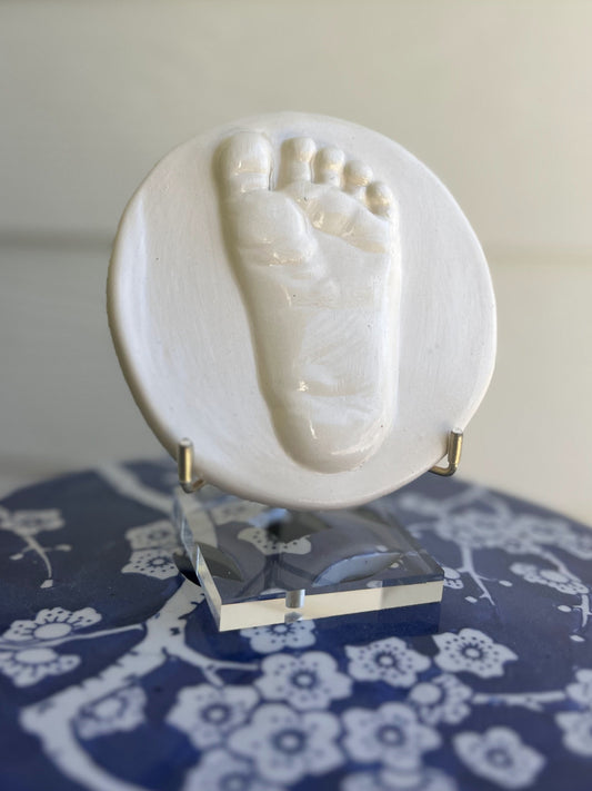 White Ceramic foot three dimensional impression on a clear Acrylic stand 