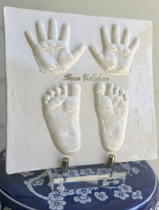 Hand-cast three-dimensional ceramic Square plaque featuring a child’s handprints and footprints, glazed and kiln fired with personalized name.